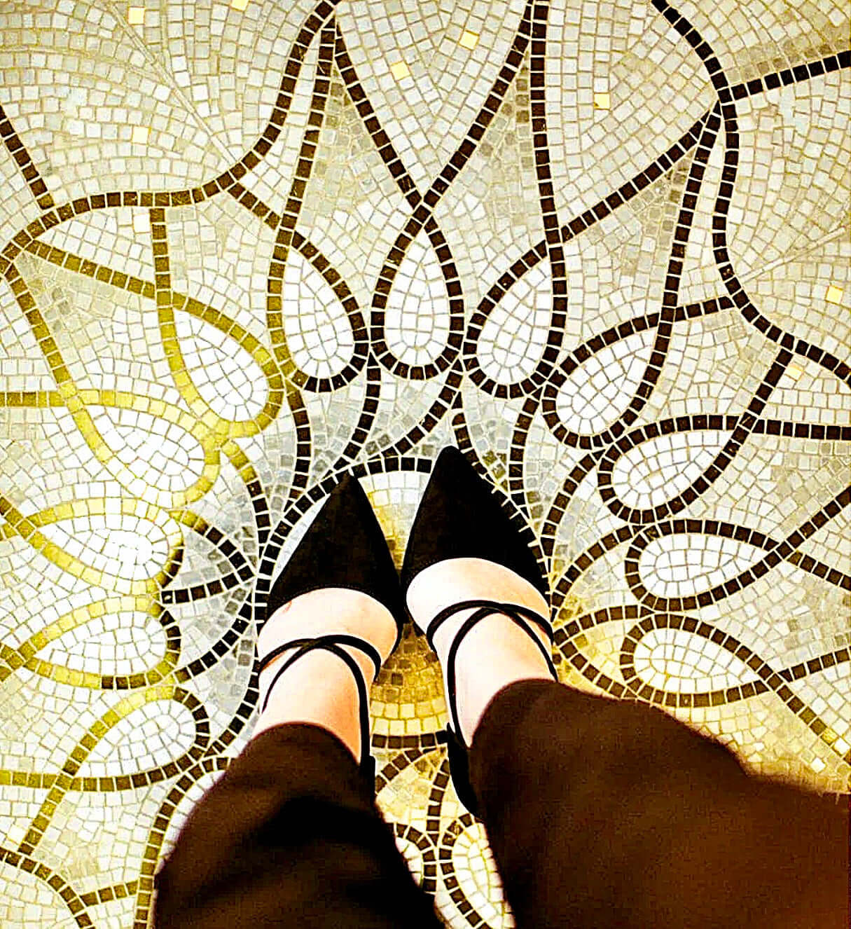 Woman standing on ornate art deco tiled floor in black high heels